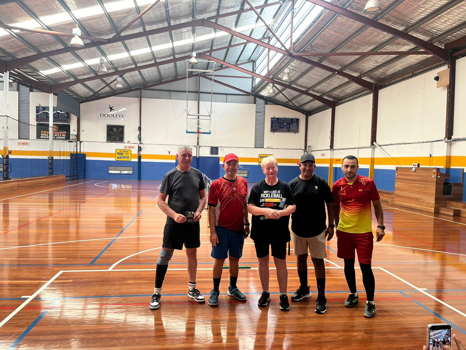 Five club members with their medals standing together in the indoor stadium