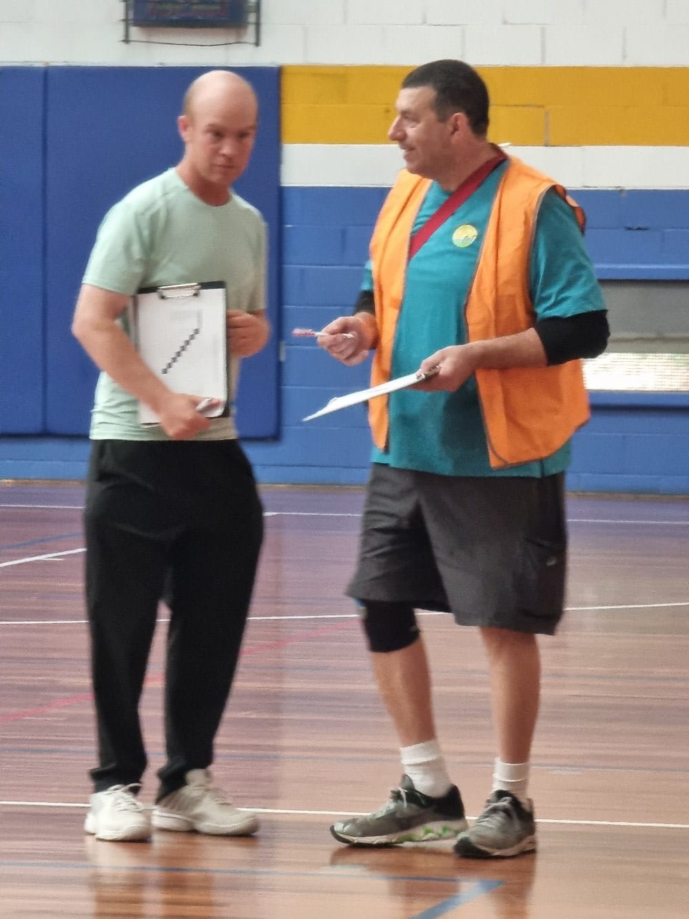Two organisers discussing the session draw with clipboards in hand