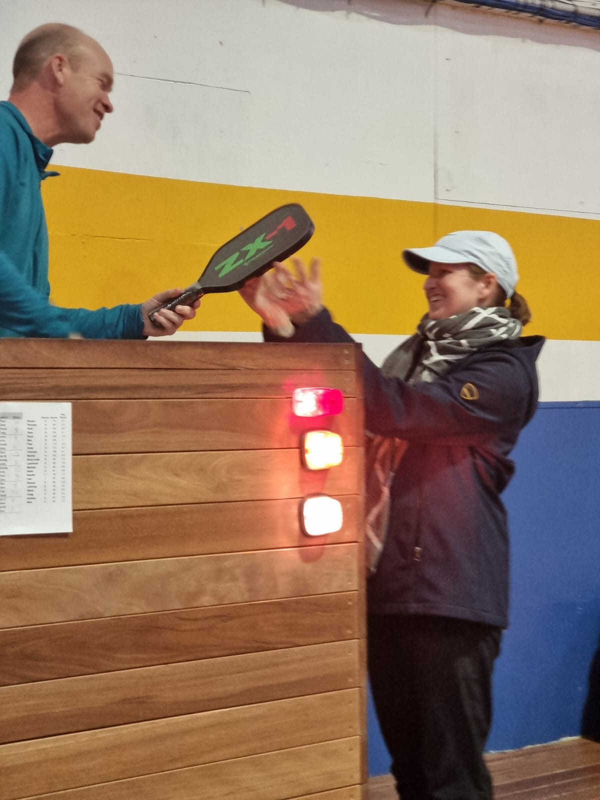 A paddle being handed over the counter to a smiling member