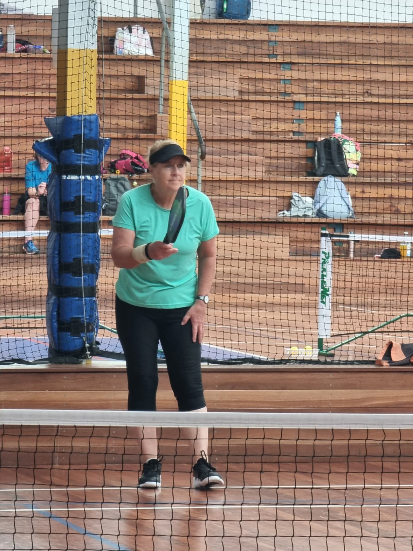 A club member in a green shirt ready at the net during a social session