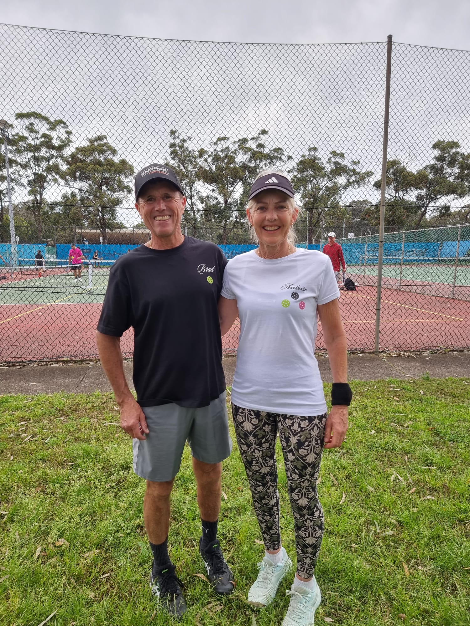 Two smiling members beside the courts after a social session