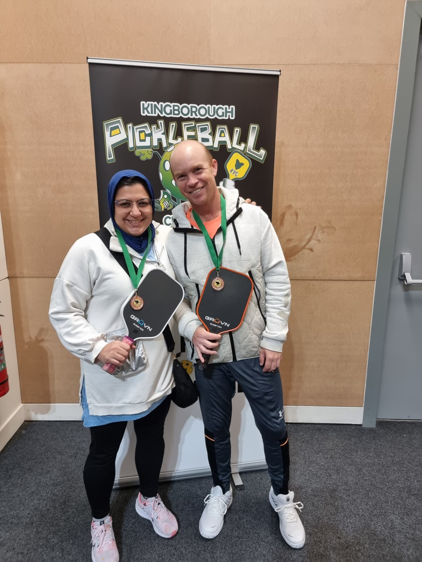 Two members with medals and paddles after a competition
