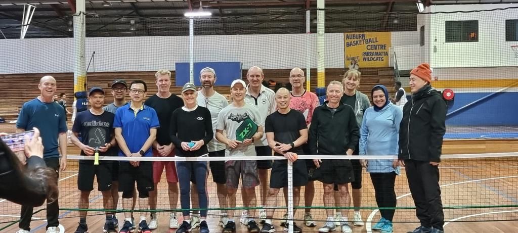 A wide line-up of club members standing together behind the net