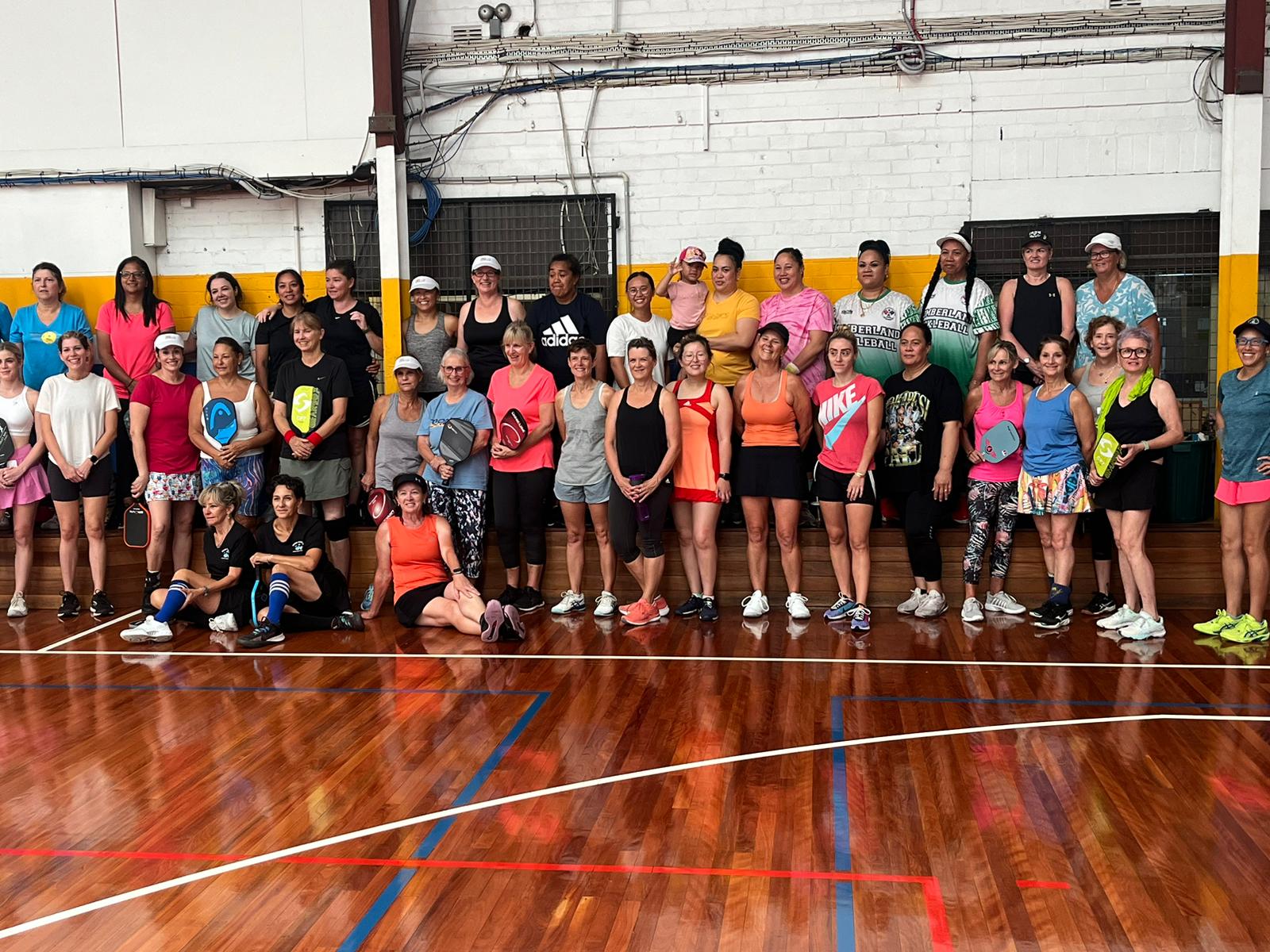 A large group of women players gathered together with their paddles before a club social