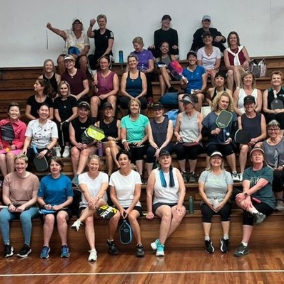 A large group of club members gathered on the courtside seating
