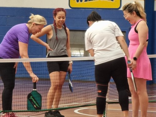 Four members sharing a laugh together at the net during a social session