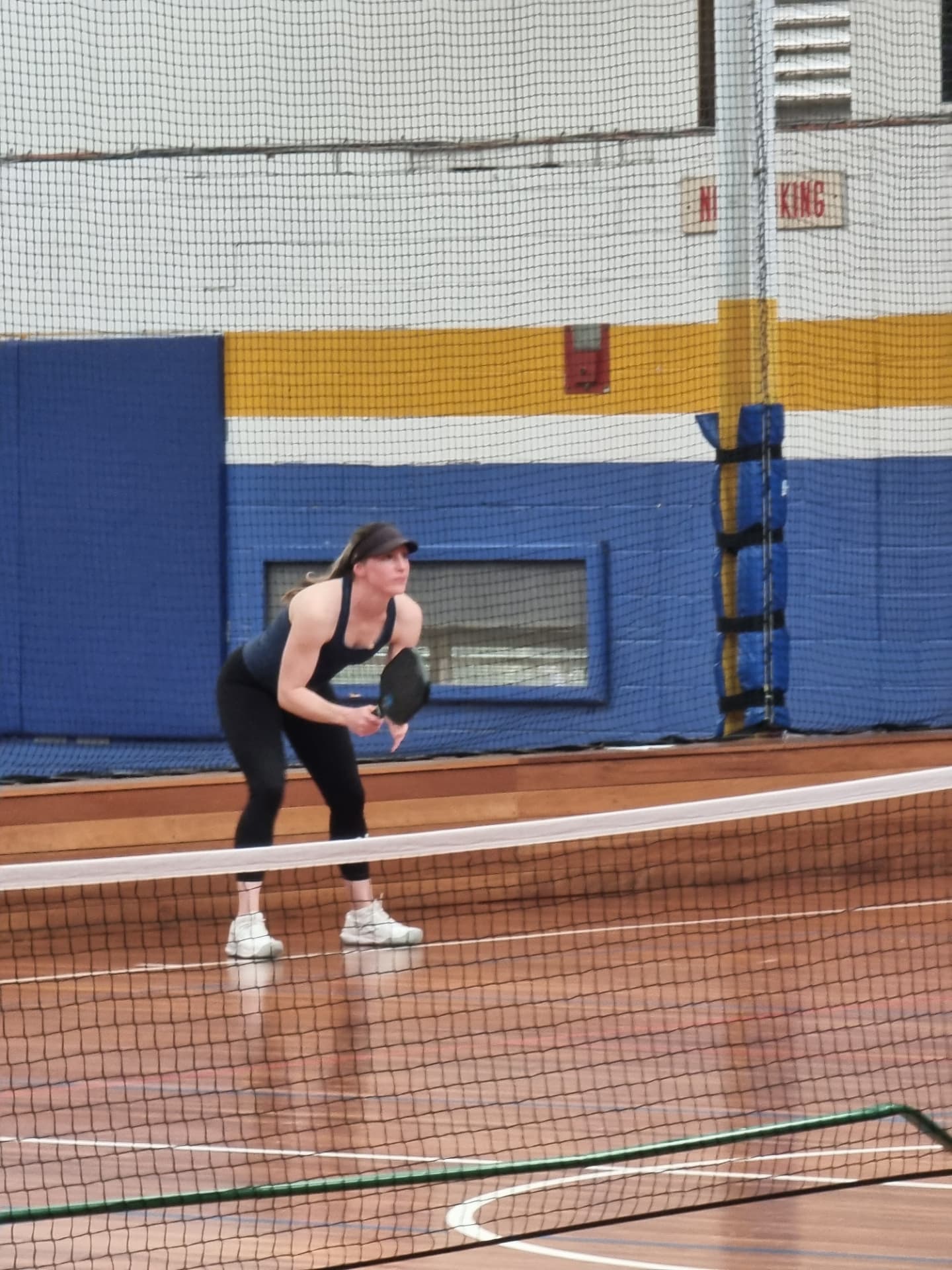 A club member in a ready stance waiting at the baseline
